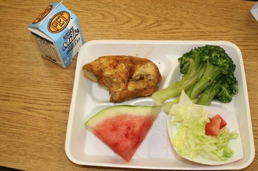  School lunch of chicken on Styrofoam tray.